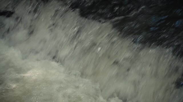 Horizontal close-up shot of fast-flowing river rapids with white water splashes and summer cicada sounds
