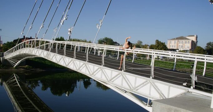 Healthy lifestyle. Outdoor yoga. Sportive female practicing active physical training on bridge performing flexible pose in park.