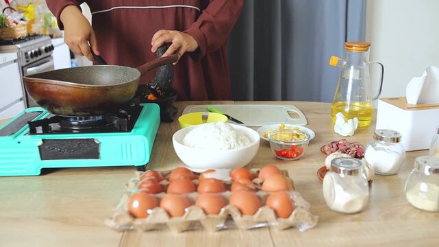 Adding ground seasonings into hot pan with spatula during Asian home cooking preparation