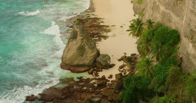 Turquoise waves crashing against rocky shore at Diamond Beach during morning in Bali Nusa Penida