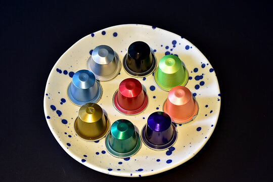 Colorful coffee capsules on ceramic plate against dark background