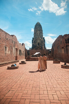 Asian traveler family, mother and child dressed in traditional Thai outfit with umbrella in sunny, summer holiday travel in Ayutthaya, Southeast Asia, ancient ruins heritage,  tourist destination.