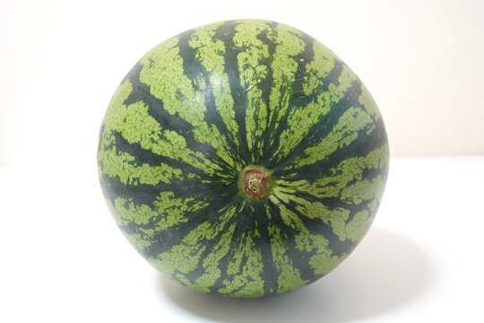 Watermelon stem end photo with radial green stripes on white bac