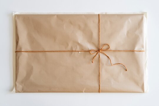 Kraft parcel paper wrapped in brown twine, featuring a tactile recycled texture and soft lighting with copy space for artisan packaging mockups