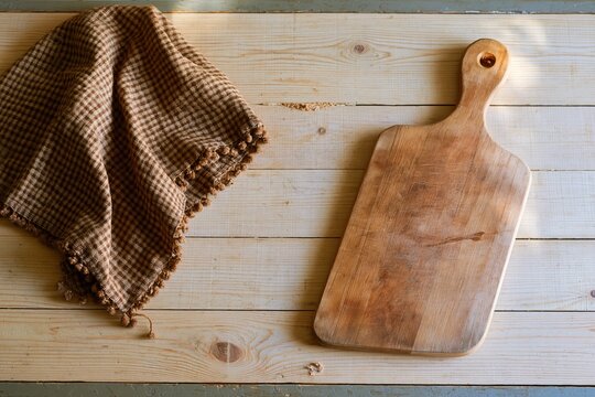 Yellow wooden plank table with a rustic chopping board and brown gingham cloth, featuring copy space for recipe and kitchen layouts