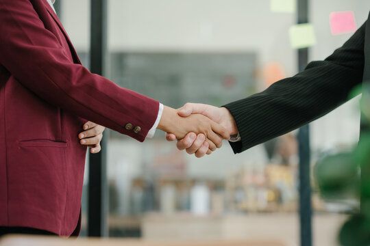 Professional business people shaking hands in a modern office, symbolizing partnership, agreement, and cooperation