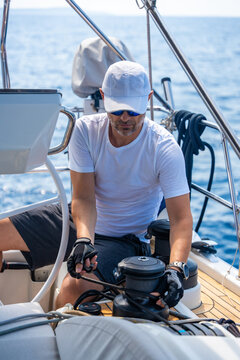 Experienced sailor trimming a sailing line on a modern yacht during an offshore passage. Seamanship, active boat handling, navigation skills and confident cruising under sail.