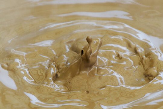 High-speed macro shot of boiling thermal mud splash creating a column and ripples in a geothermal hot spring.