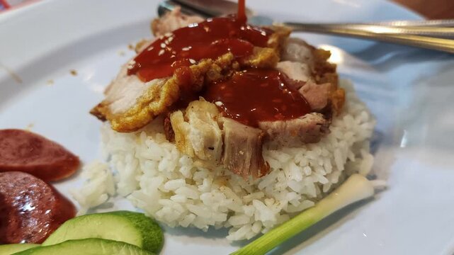 Pouring Sweet Red Sauce Over Thai BBQ Pork and Crispy Pork with Rice