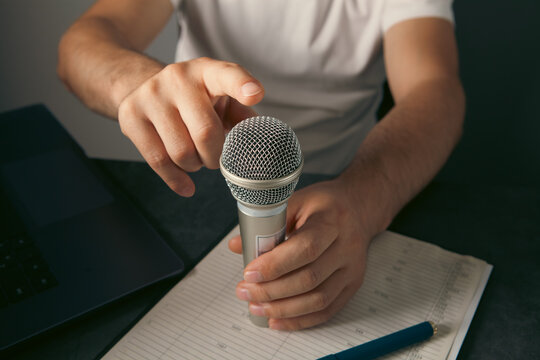 Man hand holding microphone and writing on clipboard on gray background, closeup