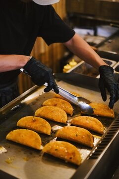 Authentic Mexican food preparation, chef grilling greasy, savory beef tacos with black nitrile gloves