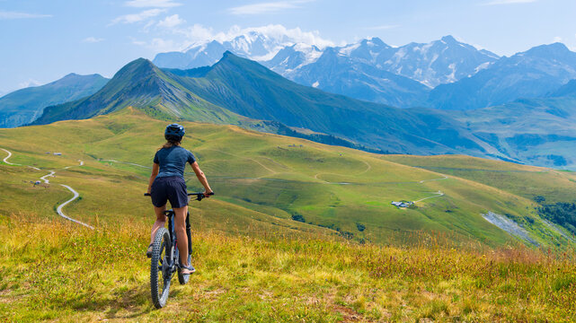 woman mountain biking on scenic alpine trail with majestic snow covered peaks in background