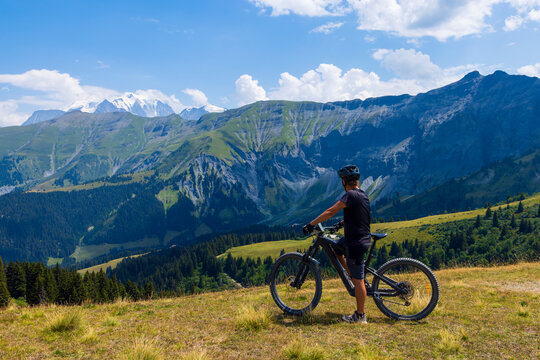 cyclist on mountain bike, electric bike enjoying scenic alpine panorama with snowy peaks in background