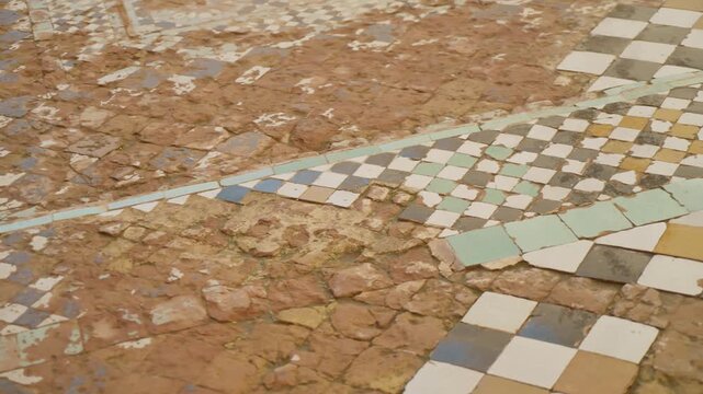 Worn mosaic tile floor with geometric patterns in historic Marrakesh setting