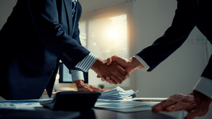 Two business partners shaking hands after successful negotiation, symbolizing deal, collaboration, and mutual trust in an office © amnaj