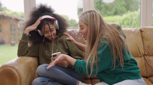 girl wearing headphones staring at her phone without taking her eyes off it, while her mother is trying to call her. The mother is shouting at her daughter, but she isn&rsquo;t paying any attention