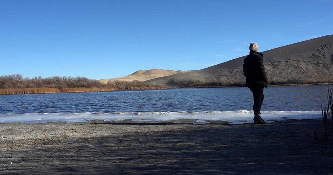 Woman walking along lake at Bruneau Dunes State Park, Idaho