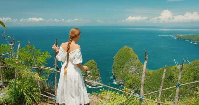 Woman with long braid enjoys the view of Kelingking Beach in Bali Nusa Penida Indonesia