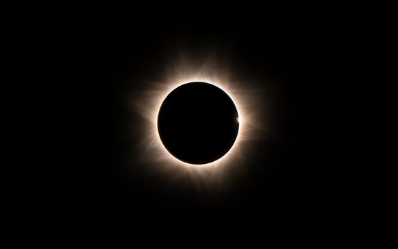 A stunning total solar eclipse showing the moon blocking the sun with a glowing corona visible in the dark sky during the celestial event