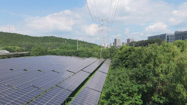Drone moving forward over solar panels and a tree lined road