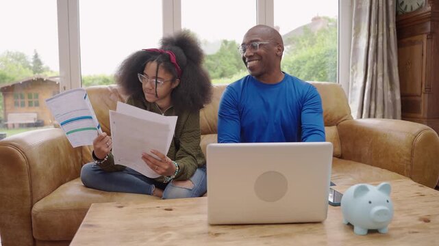 Parents and child working together on homework at home or discussing the cost of studying at a university or college 