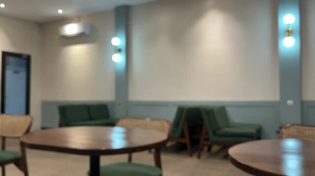Blurred of interior cafe or coffee shop. empty wooden tables And chairs,  indoor seating. restaurant. interior. green, nature, wall, lamps, lights, warm. night. dine in, dining. work from cafe. brown.