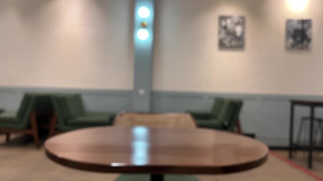 Blurred of interior cafe or coffee shop. empty wooden tables And chairs,  indoor seating. restaurant. interior. green, nature, wall, lamps, lights, warm. night. dine in, dining. work from cafe. brown.