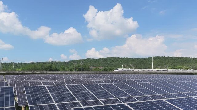 High speed train passing a solar farm under blue sky