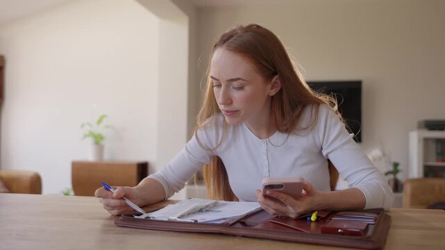 Woman studying and taking notes at home in a cozy setting during the afternoon hours