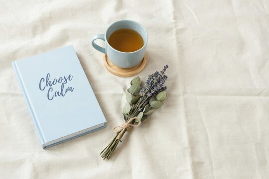 Light blue book with choose calm text, tea cup, and dried lavender sprigs