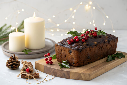 Christmas fruitcake loaf decorated with red berries and festive candles