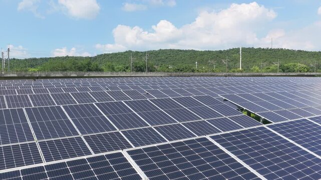 Aerial view moving across solar panels and green hills