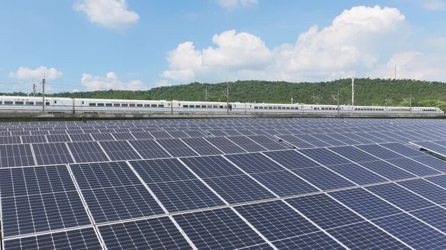 High speed train passing solar panels beside green hills