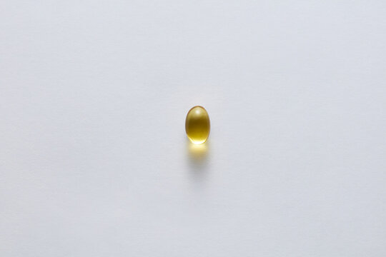 Single Yellow Softgel Capsule Vitamin Supplement on White Background