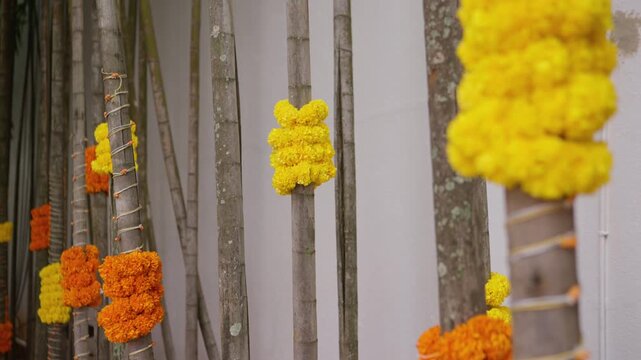 Rows of bamboo poles decorated with yellow and orange marigold garlands outdoors