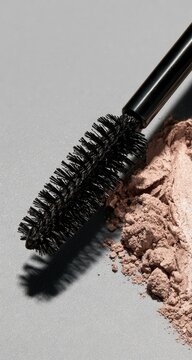 Close-up of a cosmetic brush next to loose powder on a gray surface