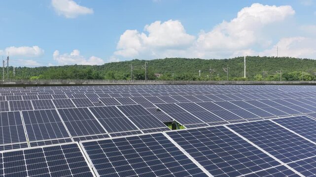 Aerial tracking shot across solar panels and green hills