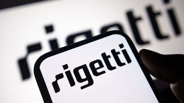 Rigetti computing logo displayed on smartphone and computer screen in dark studio setting.