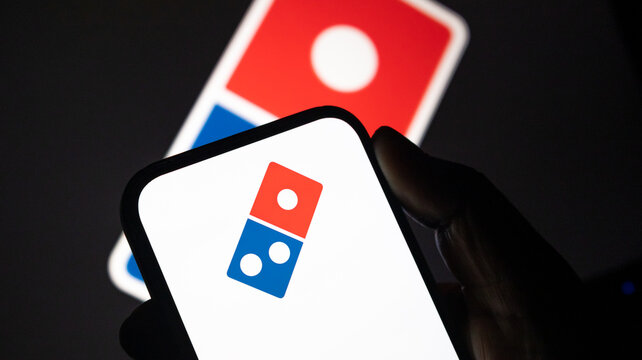 Dominos Pizza brand logo displayed on smartphone screen against blurred company icon background for food service marketing.