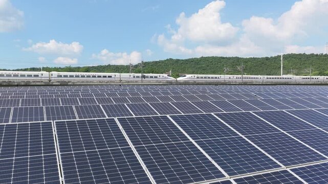 High speed train passing a solar farm in a green landscape