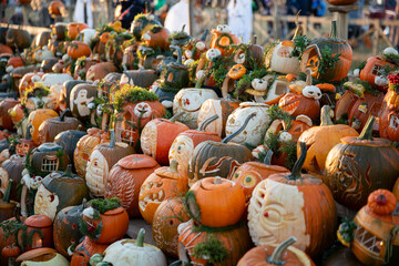 Fototapeta premium Intricately carved jack-o'-lantern pumpkins with moss decorate an outdoor autumn folk festival, showcasing handmade Halloween craftsmanship.
