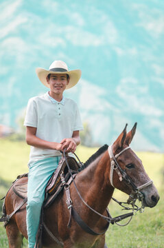 Young boy smiling riding a mule outdoors