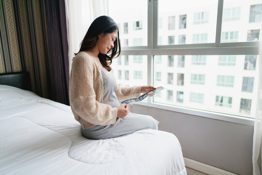 Pregnant woman looking at ultra sound paper of her Baby