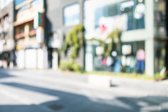 Abstract blurred modern urban shopping street background with clothing boutique storefronts and green plants