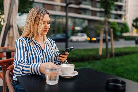 Woman using smartphone relaxing at outdoor cafe