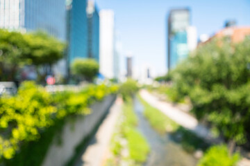 Fototapeta premium Abstract blurred modern downtown Seoul Cheonggyecheon stream background with skyscrapers and green trees