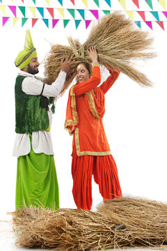 Man helping a woman carry a bale of hay 
