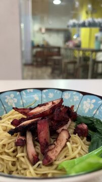 Close up view of noodle on the bowl. chicken charsiu and mustard greens leaves. side, front. mie, bakmi. copy space, empty, free, negative, text, design. vertical, potrait. lights, bright