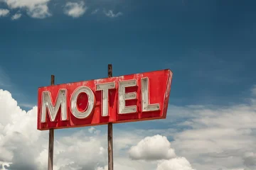 Vintage red mid-century neon motel sign, blue sky background, retro summer road trip and travel © Delphotostock
