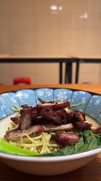 Close up view of noodle on the bowl. chicken charsiu and mustard greens leaves. side, front. mie, bakmi. copy space, empty, free, negative, text, design. vertical, potrait. lights, bright